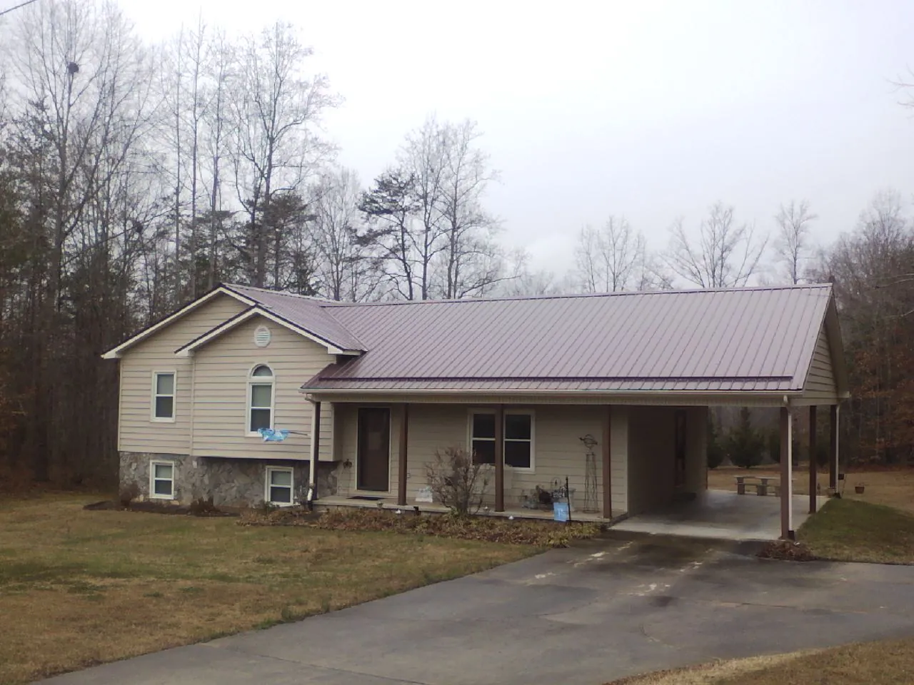 Burgundy metal roof on a tan split level home with an attached carport in Curtice