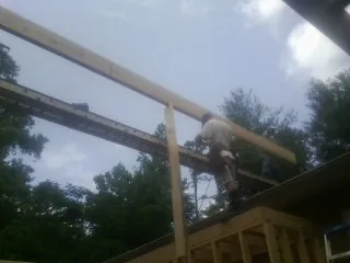 Carpenter setting a ridge beam over a new addition frame — Ice Dam Removal by Roofing Brothers in Curtice