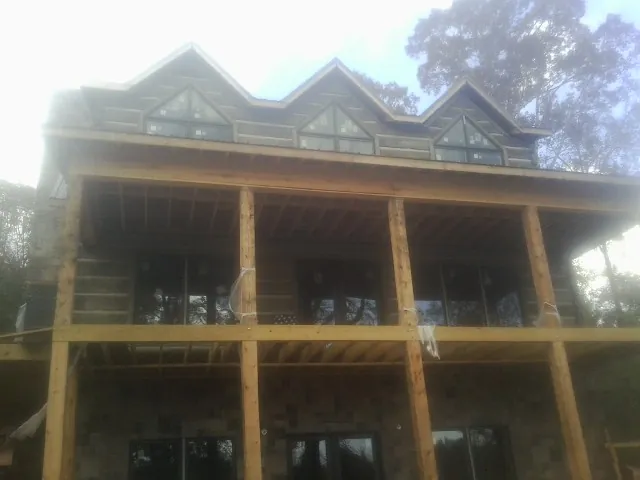 Dormers and porch framing on a large log home under construction — Roof Coating work by our crew in Curtice