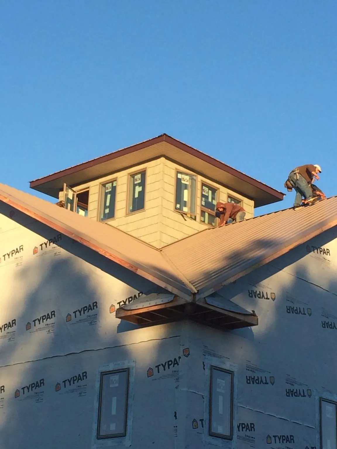 Roofers working around a rooftop cupola on a new metal roof at sunset — Roof Waterproofing in Curtice by Roofing Brothers